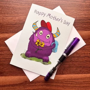 Monster Mother's Day card by Tom Serafini featuring a fluffy purple monster with sunflowers displayed on a wood desk with white envelope
